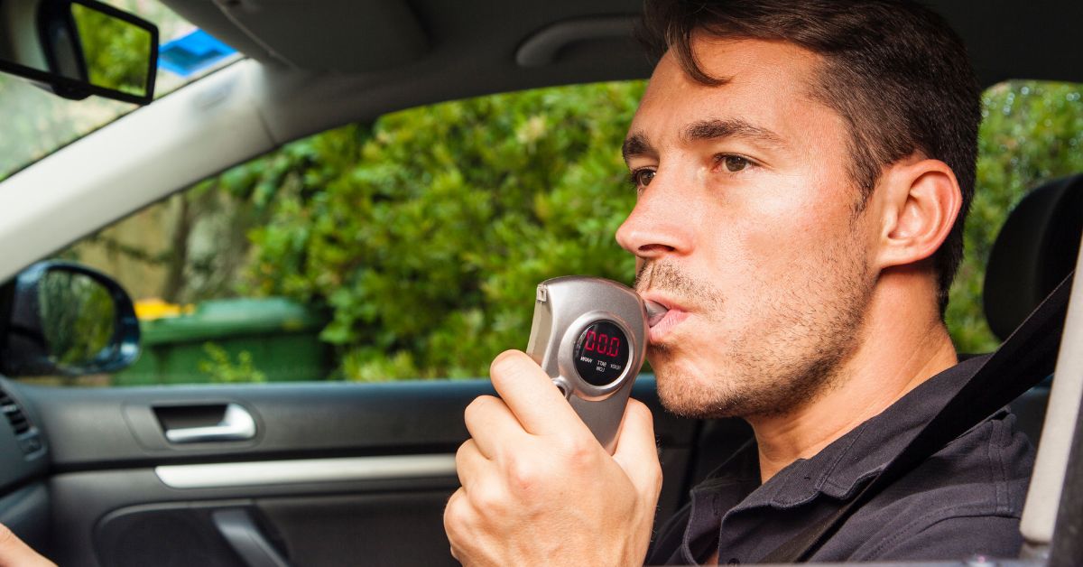 man in car blowing into ignition interlock device